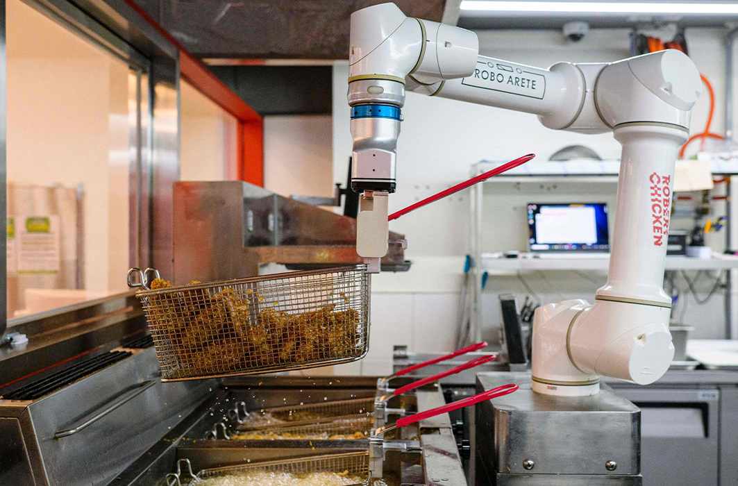Un bras robotisé prépare du poulet frit.