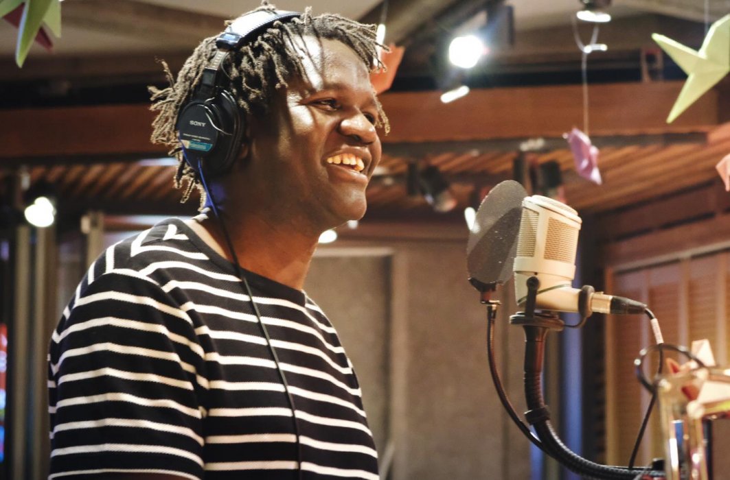 L'humoriste et biologiste Boucar Diouf parle au micro. Il est souriant.