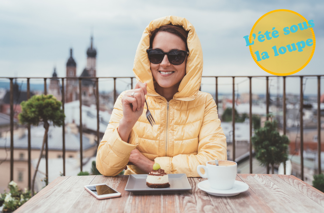 Une femme, vêtue de ses vêtements d'hiver, mange un gâteau sur une terrasse. 