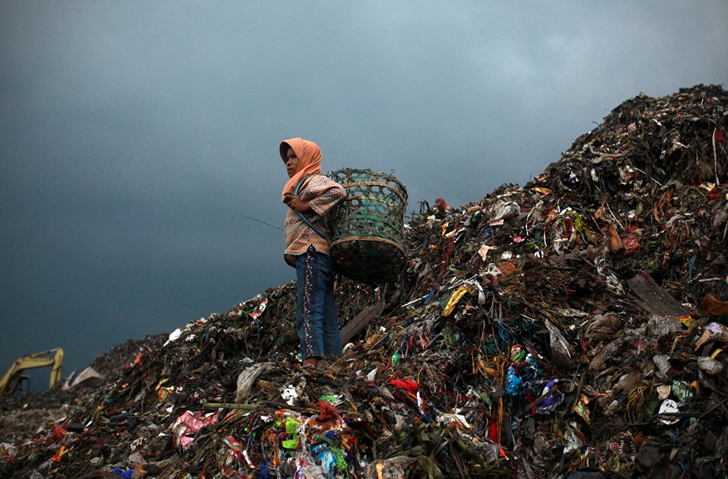 Une jeune femme récolte des objets dans une décharge.