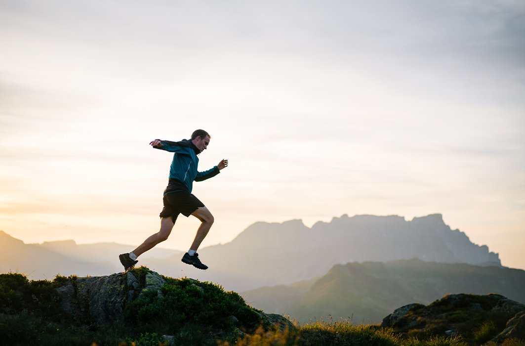 Un homme en pleine course sur un sommet rocheux.