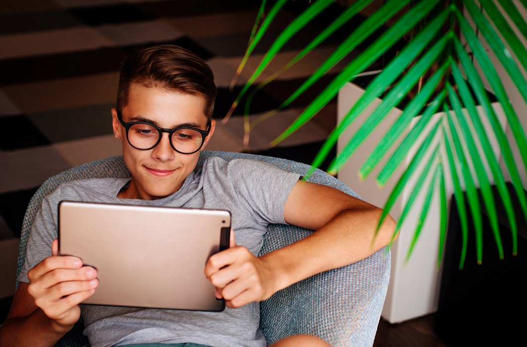 Un enfant portant des lunettes regarde une tablette.