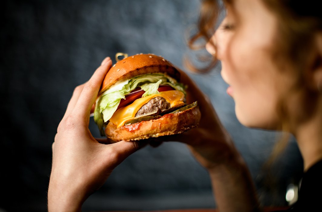 Une femme mange un hamburger.