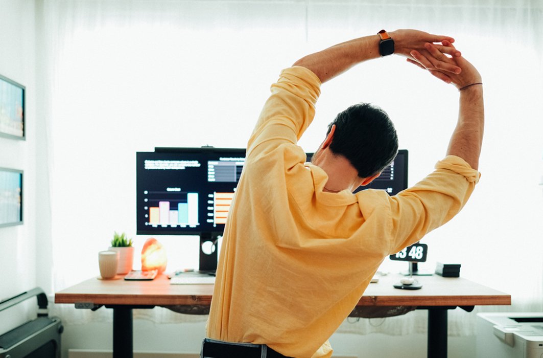 Une personne s'étire à son bureau. Une personne s'étire à son bureau.