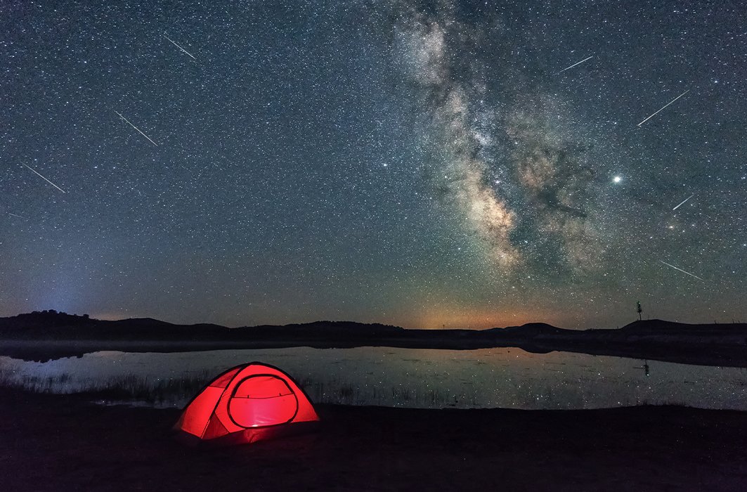 Une tente éclairée sous un ciel étoilé.