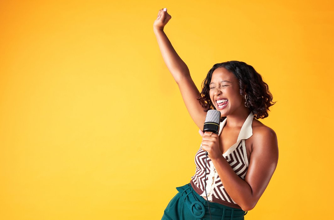 Une femme chante devant un fond jaune éclatant.
