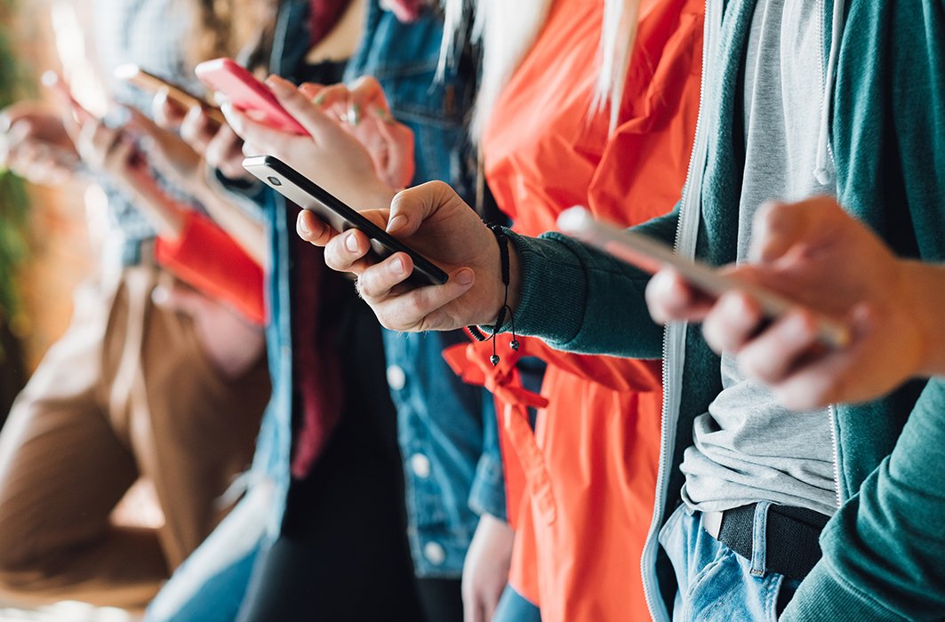 Des personnes tiennent des téléphones.